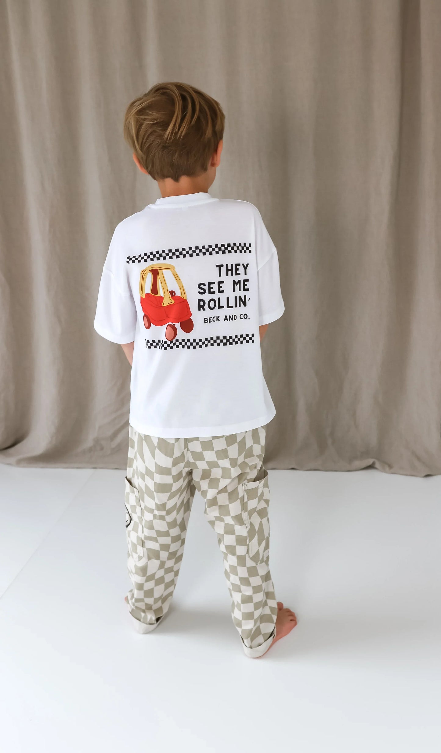 Child wearing Beck and Co. streetwear tee with car print and checkered pants, skater style