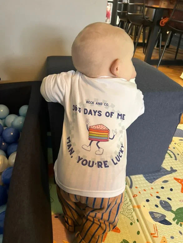 Baby in Beck and Co. kids streetwear tee with birthday cake graphic, playful print, and striped pants