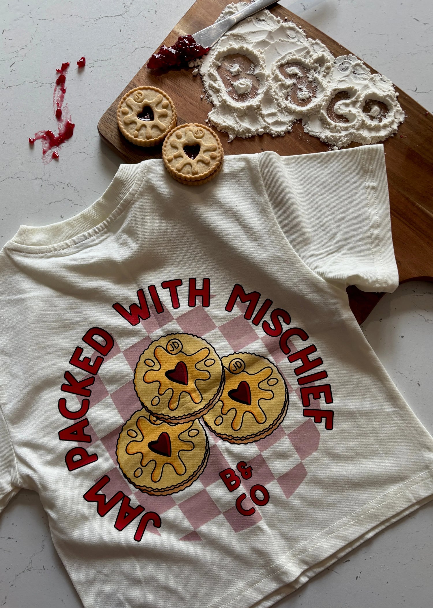 Children’s streetwear Beck and Co. tee with jam biscuit print, cookies, and baking scene.