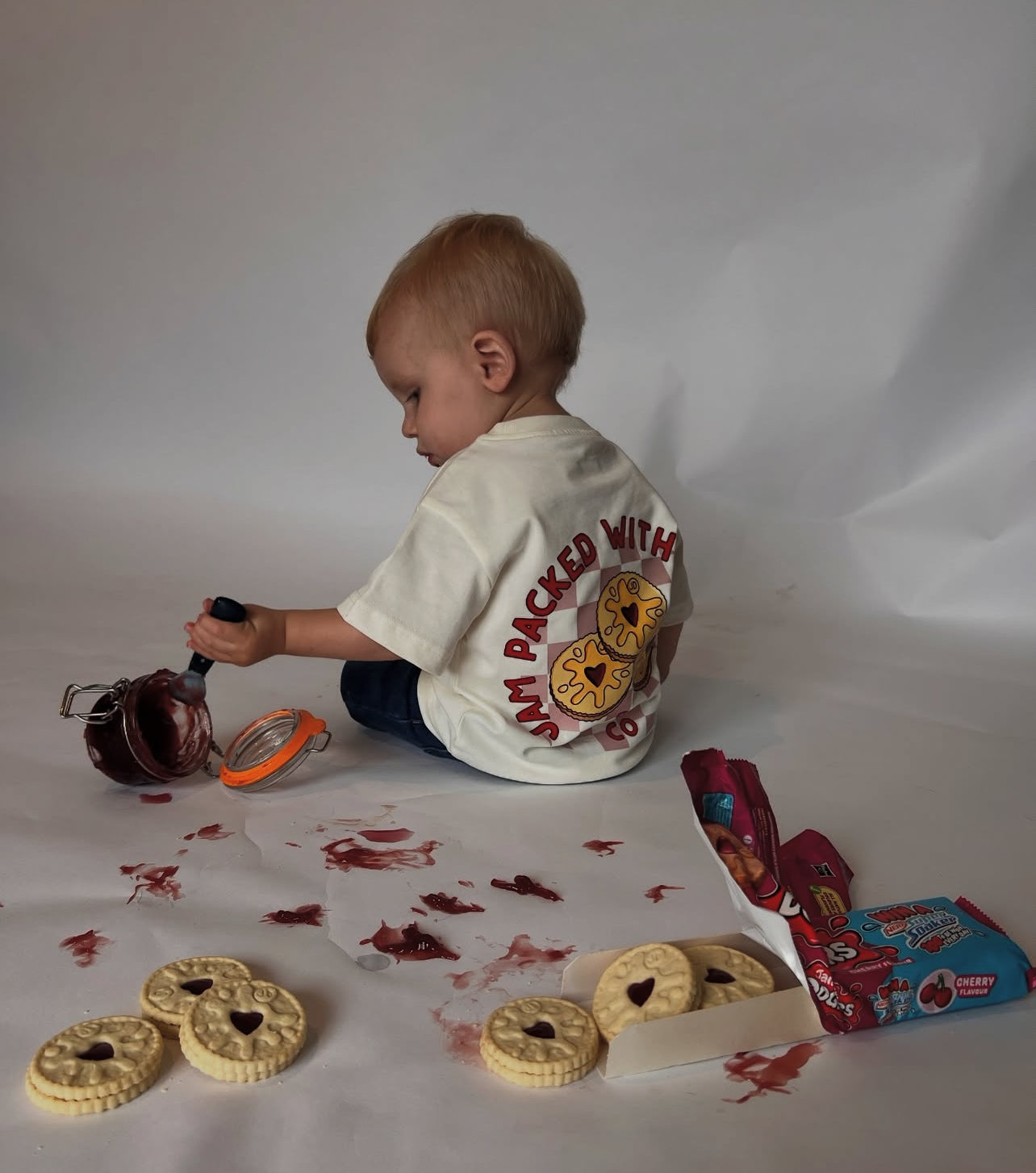 Child playing with toy car and cookies on a white background