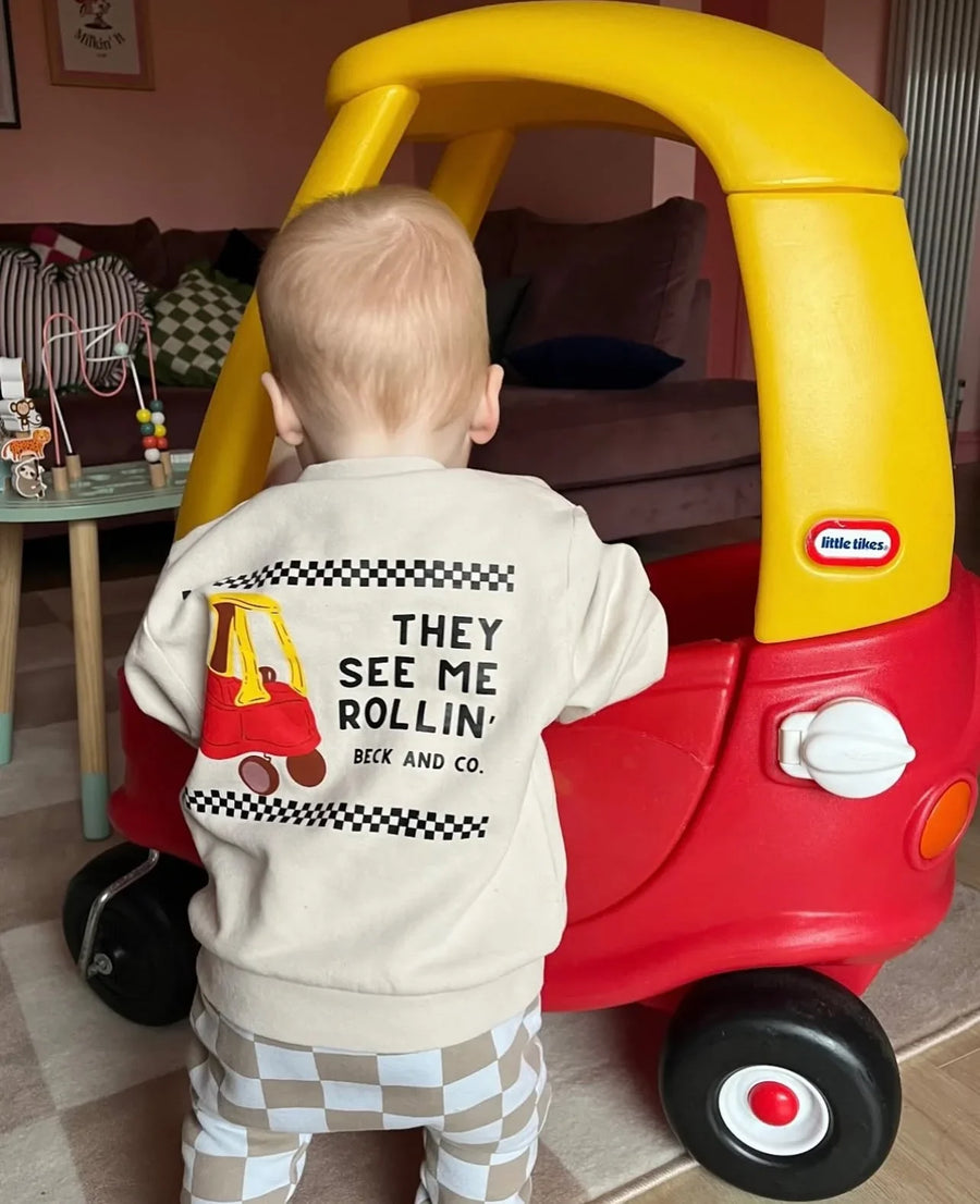 Toddler wearing Beck and Co. streetwear sweatshirt by a red and yellow toy car indoors