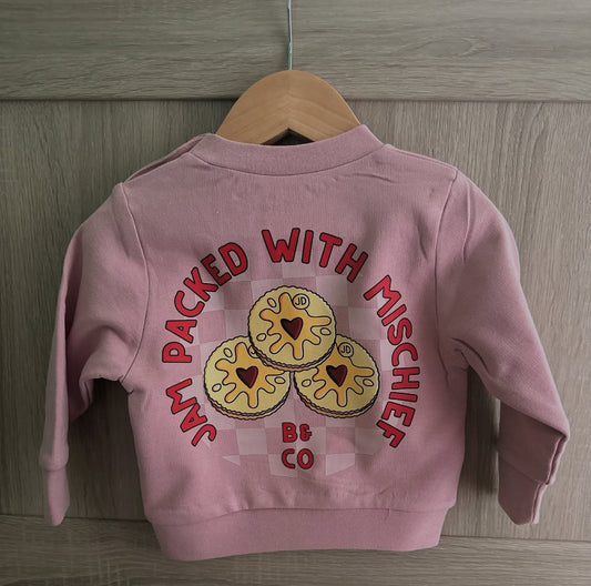 Pink children's jacket with cookie design and text on a wooden background