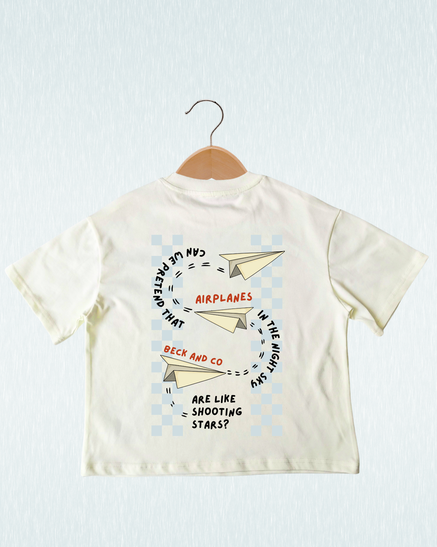 Children's t-shirt with airplane design and text on a hanger against a light blue background