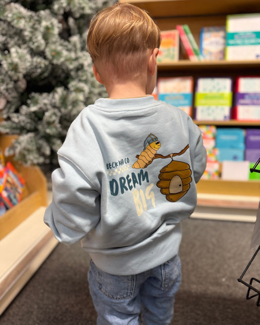 Child wearing a light blue hoodie with a caterpillar design and text in a bookstore.