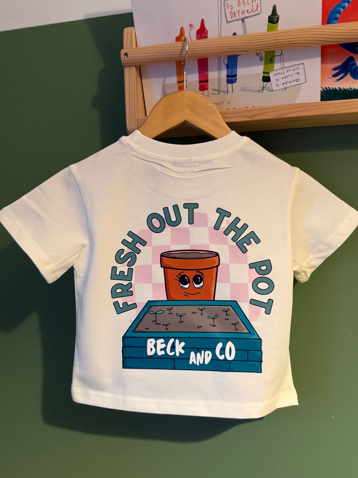 White t-shirt with cartoon design and text on a green surface