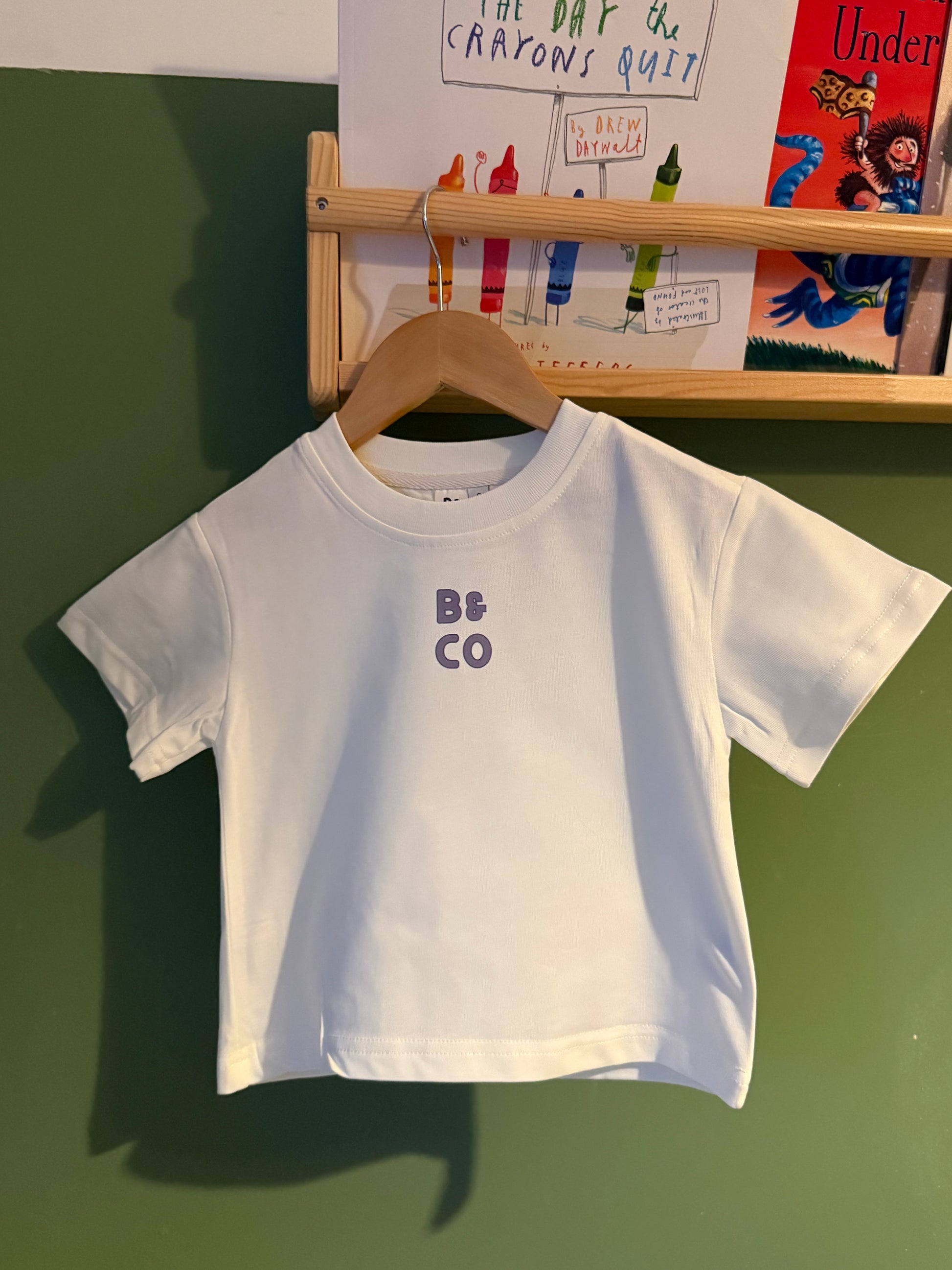 White t-shirt with 'B&Co' logo on a green surface