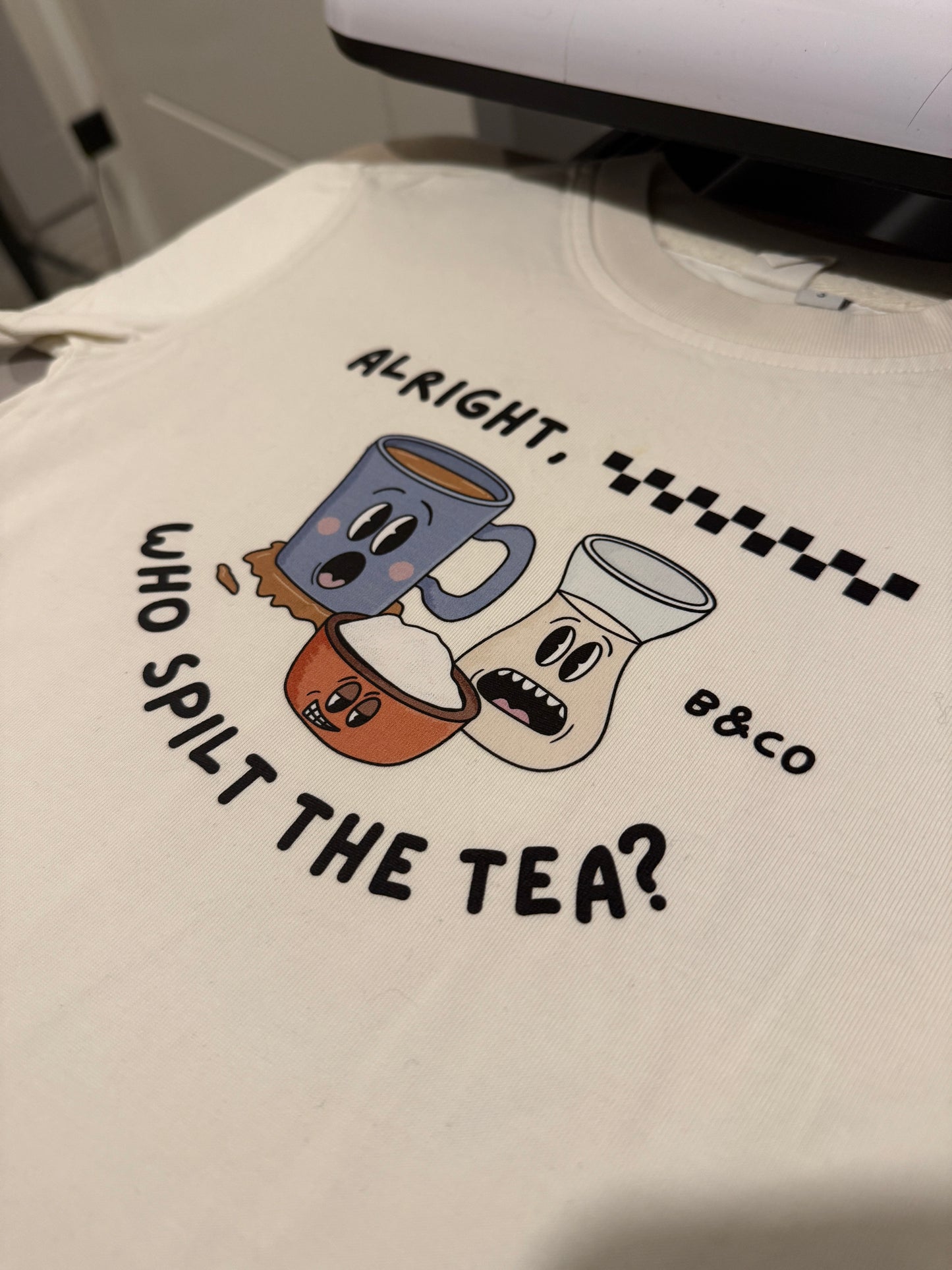 White t-shirt with cartoon teacups and text design on a white background