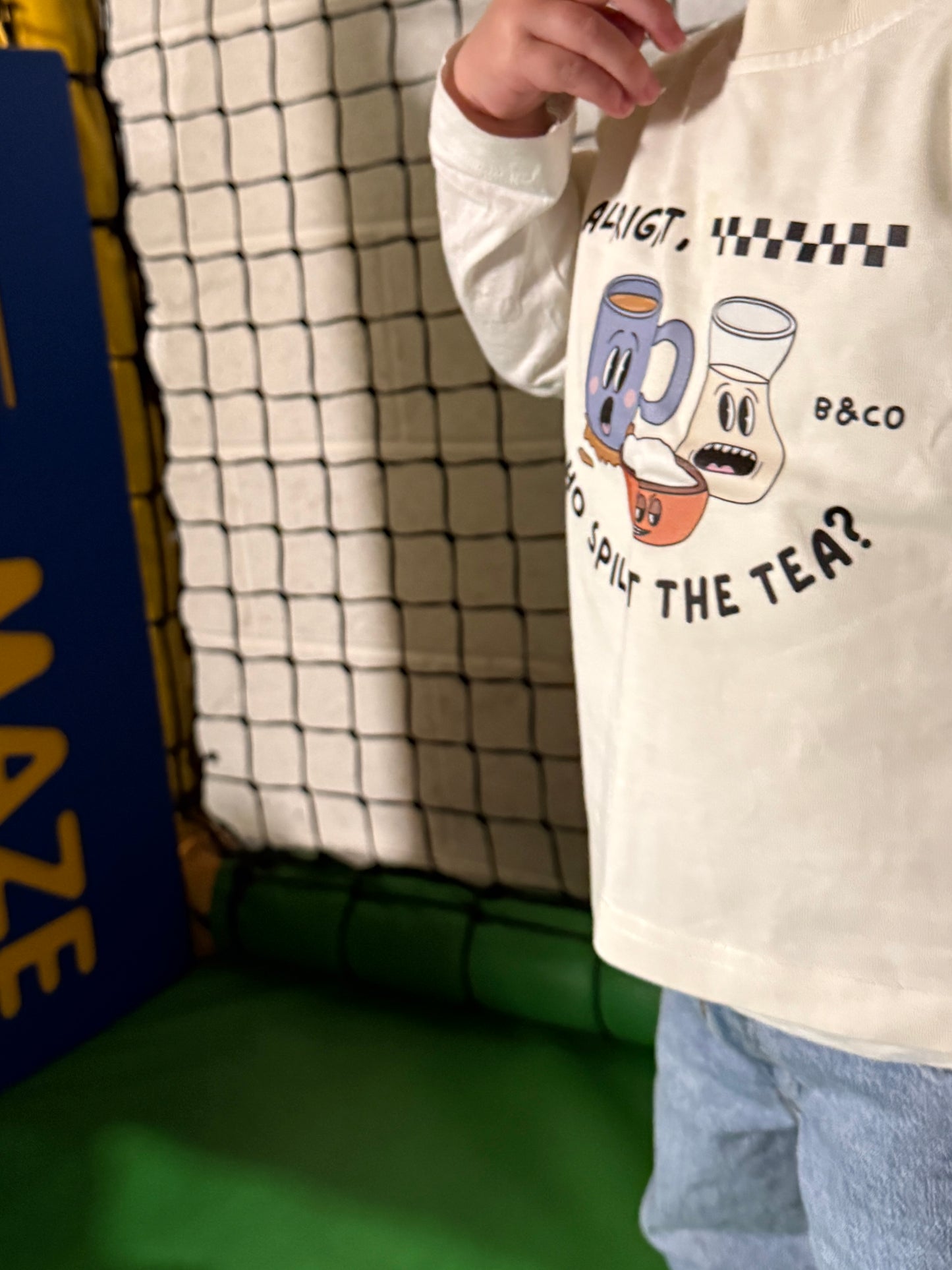 Person wearing a white sweatshirt with a graphic design and text, standing indoors.